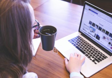 person holding a coffee cup and looking at a computer